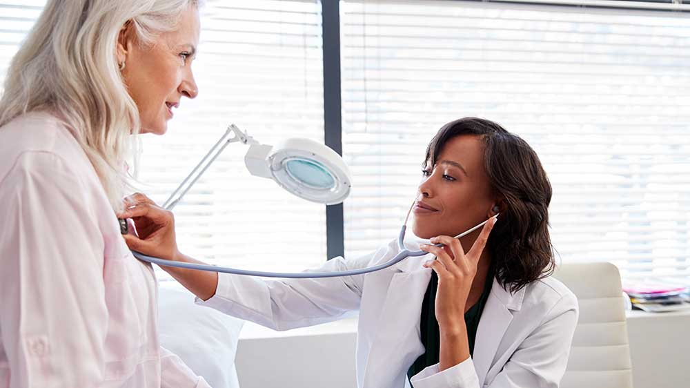doctor listening to older womans heart